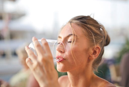 Close-up of a woman drinking water with a serene expression outdoors.